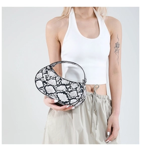Detail of hobo bag with black and white python print on model wearing casual outfit