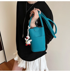 Détail du sac seau bleu cyan à grain litchi avec un pendentif canard blanc mignon