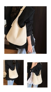 Detail of minimalist cream leather tote bag featuring lychee texture and golden metal buckle
