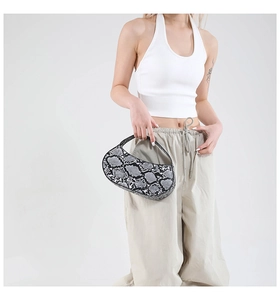 Detailed view of women's snakeskin pattern crescent underarm bag shown on a model