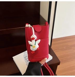 Détail du sac bandoulière rouge texture litchi avec charmant pendentif canard blanc