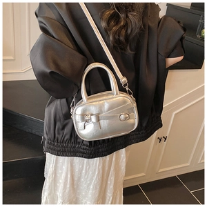 Detail of silver bow bowling bag with metallic texture shown on model in stairwell