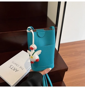 Détail du sac de téléphone bleu en cuir grainé avec un pendentif canard blanc mignon
