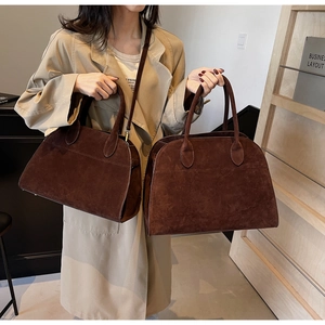 Detalle de dos tamaños de bolsos retro de ante marrón oscuro con asas cilíndricas