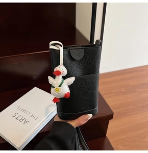 Détail d'un sac à téléphone en cuir grainé noir avec un pendentif canard blanc mignon