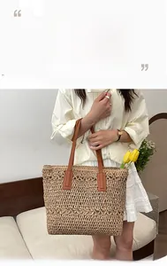 Detail of hand-woven straw tote with premium brown leather handles for summer beach