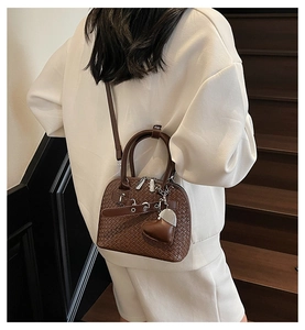 Detail of brown woven leather texture on a shell bag with a heart charm and silver zipper