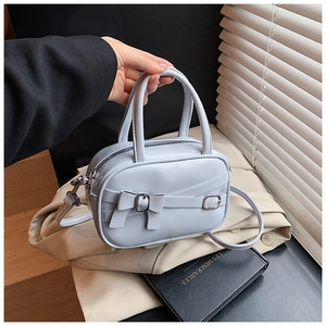 Detail of light blue leather bowling bag featuring a front bow and silver metal buckle