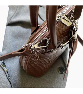 Detail of woven brown PU leather shell bag with polished silver hardware and zipper