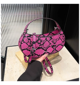 Detail of fuchsia snake print half-moon bag featuring embossed leather and logo text