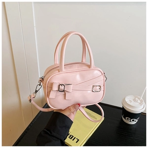 Pink bowling bag detail featuring a decorative bow and adjustable leather shoulder strap