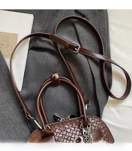 Detail of dark brown woven leather shell bag with adjustable strap and silver chain