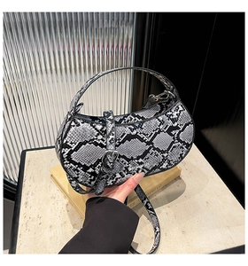 Detail of grey snakeskin crescent handbag on marble with silver buckle and adjustable strap
