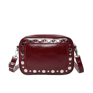 Chique bordeaux lakleren crossbody tas met zilveren klinknagels op witte achtergrond