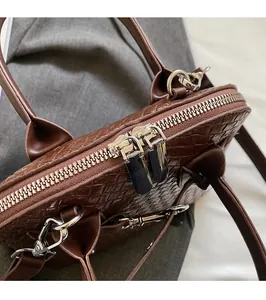 Close-up of brown woven texture handbag featuring smooth silver double metal zippers