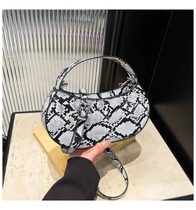 Detail of black and white snakeskin pattern crescent handbag with metal buckle closure