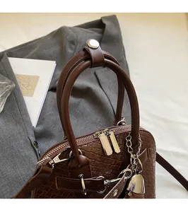 Close-up of brown woven shell bag featuring dual silver zippers and sturdy round handles