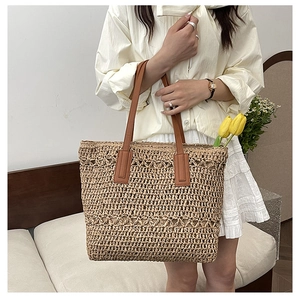 Detailed macro view of woven straw texture and premium brown leather handles on large tote bag