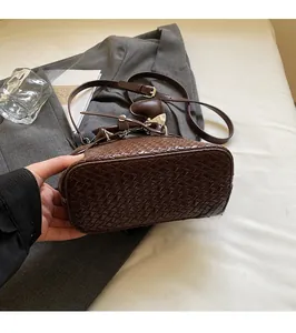 Detail of dark brown woven texture PU leather bucket bag with adjustable crossbody strap