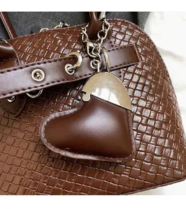 Detail of dark brown woven texture PU bag with heart pendant and silver hardware
