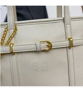 Close-up of white lychee pattern leather handbag with elegant gold metal hardware details