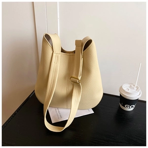 Detailed close-up of beige lychee grain leather tote bag with elegant gold hardware