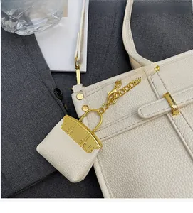 Detail of white lychee leather mini bag charm with gold buckle on a tote bag