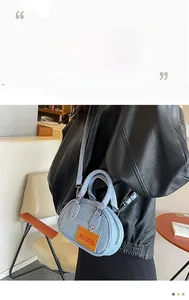 Blue denim mini Boston bag with orange Jeans patch shown worn as a crossbody purse