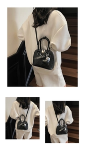 Detail of black woven texture shell bag with heart charm shown on a white hoodie