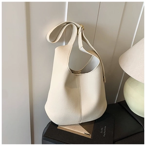 Detailed macro view of cream pebbled leather texture and golden metal strap buckle on tote bag