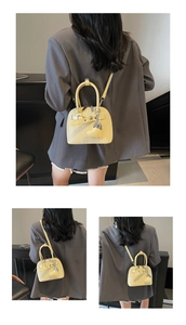 Detail of light yellow woven shell bag with heart charm and adjustable shoulder strap
