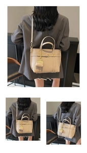 Detail of beige pebble leather handbag featuring a mini pouch charm and gold hardware