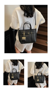 Detail view of black lychee grain leather handbag with gold buckle and mini charm bag
