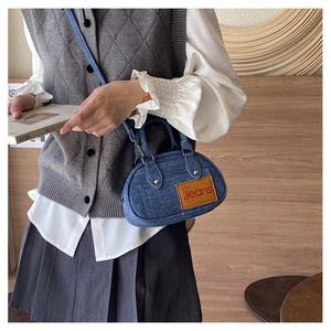 Detail of blue denim mini bag with brown leather patch and red Jeans text engraving