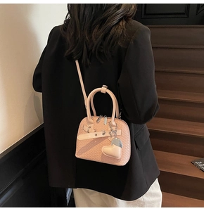 Detailed woven texture of a light pink mini shell bag with silver hardware and heart charm