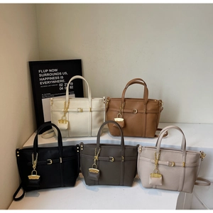Detail showing five colors of lychee grain leather tote bags with mini charm and gold hardware