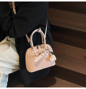 Close-up of peach pink shell bag with woven texture worn by model in black blazer