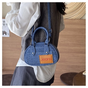 Detailed close-up of blue denim crossbody bag with vintage leather jeans tag detail