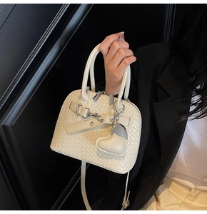 Macro detail of cream woven texture PU leather shell bag with silver heart charm decoration