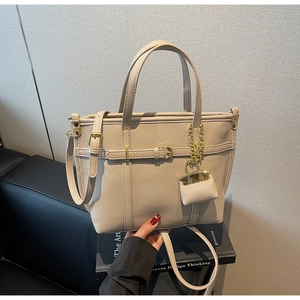 Detail of beige lychee textured leather tote bag with gold hardware and small pouch