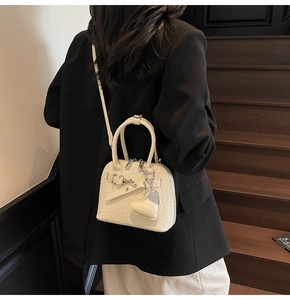 Detail of cream woven leather handbag featuring silver hardware and heart charm decoration