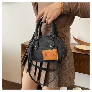 Detailed shot of black denim bowling bag with double handles and metal stud accents