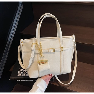 Close-up of white lychee textured tote bag with gold hardware and mini bag charm