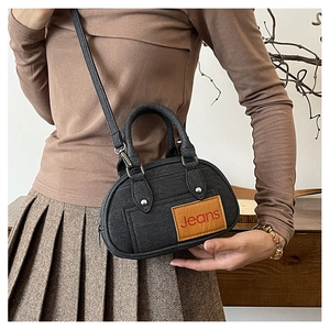 Detail view of denim texture handbag featuring a brown leather patch and Jeans embroidery