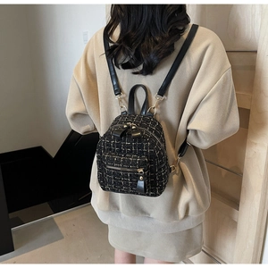 Dettaglio di un mini zaino in tweed a scacchi indossato con un completo in maglia beige