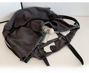Detalle de bolso grande gris oscuro con cierre de cordón y bolsillo interior con cremallera
