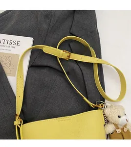 Detail of yellow lychee leather bucket bag with gold buckle and cute bear charm
