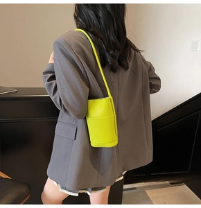 Fluorescent green lychee texture mini bag worn by model over a grey blazer