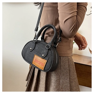 Close-up of black denim style bowling bag with jeans patch and silver zipper details