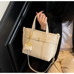 Detailed view of the creamy white tote bag featuring lychee texture leather and gold hardware